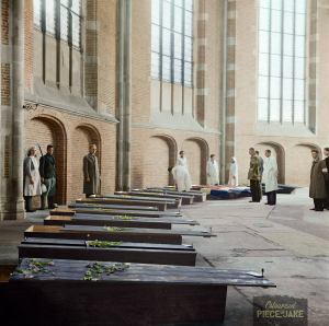 Kisten met de overledenen in de Grote Kerk in Deventer, waarschijnlijk is de achtste kist (waar de man bij staat) de kist waarin Corry ligt. (Foto W. van der Poll (1945) collectie Anefo - Nationaal Archief)